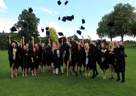Graduates in gowns throwing their mortarboards into the air, Goldsmiths, University of London,