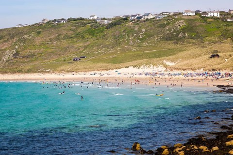 Coastal scenery with busy crowded sandy beach, Sennan Cove, Land's End, Cornwall, England, UK