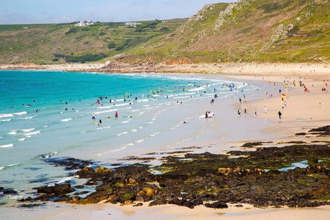 Coastal scenery with busy crowded sandy beach, Sennan Cove, Land's End, Cornwall, England, UK