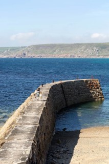Woman and girl walking on breakwater quay, Sennen Cove, Land's End, Cornwall, England, UK