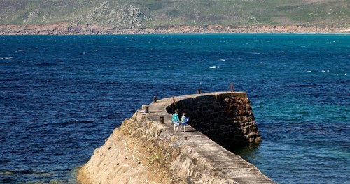 Woman and girl walking on breakwater quay, Sennen Cove, Land's End, Cornwall, England, UK