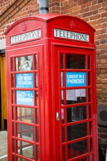 Concert in a Phonebox in old red traditional phone box booth, Snape Maltings, Suffolk, England, UK