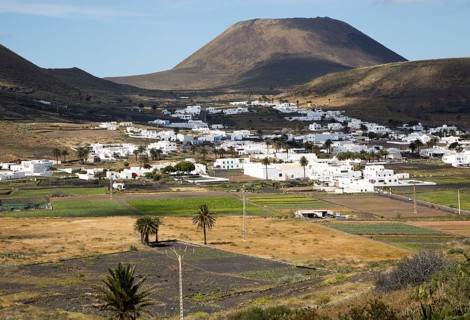 View over cactus plants and whitewashed houses to Monte Corona volcano cone, village of Maguez,