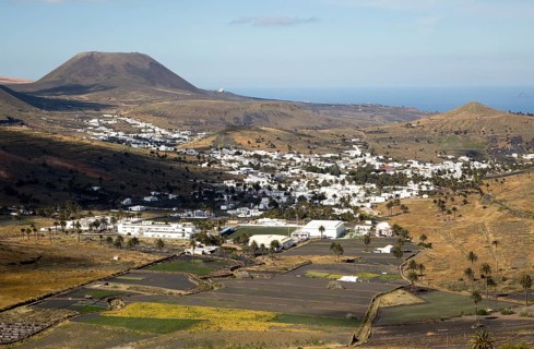 View over cactus plants and whitewashed houses to Monte Corona volcano cone, village of Haria,
