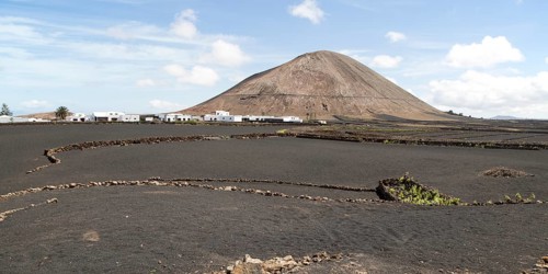 Volcano cone and black volcanic soil farmland, near Tinajo, Lanzarote, Canary Islands, Spain,