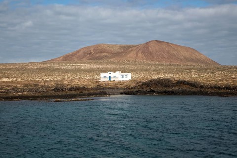 Isolated whitewashed house and Agujas Grandes volcano, La Isla Graciosa, Lanzarote, Canary Islands,