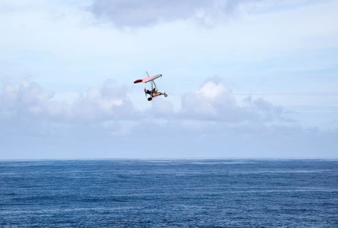Person flying microlight plane over the ocean, Caleta de Caballo, Lanzarote, Canary islands, Spain,