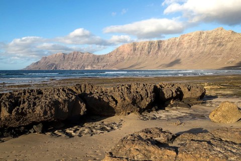 Late afternoon light on beach and cliffs La Caleta de Famara, Lanzarote, Canary islands, Spain,