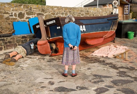 Man painting small fishing boat watched by an elderly woman presumably his mother, Coverack,