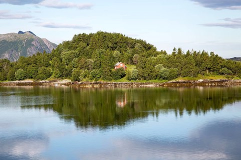 Isolated coastal house on small wooded island near Ornes, Nordland, Norway, Europe