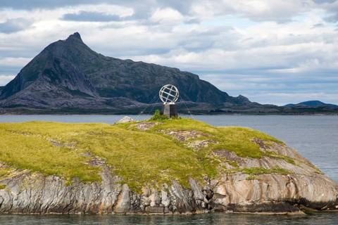 Monument marker to show crossing the Arctic Circle heading south on small island, Norway, Europe