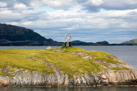 Monument marker to show crossing the Arctic Circle heading south on small island, Norway, Europe