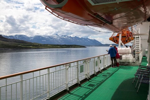 Two people on deck viewing scenery on Hurtigruten ferry ship, near the Arctic Circle crossing,