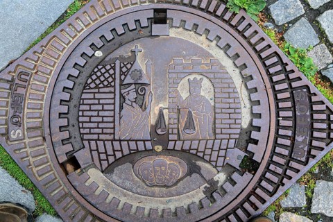 Looking down on old iron manhole cover in city of Trondheim, Norway, Europe