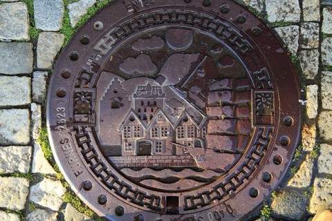 Looking down on old metal manhole cover city of Bergen, Norway, Europe