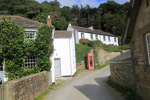 Traditional red telephone box and whitewashed corsages, village of Durgan, Cornwall, England, UK