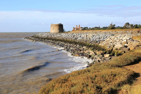 Martello tower W defended by rock armour from coastal erosion, East Lane, Bawdsey, Suffolk,