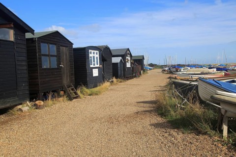 Dinghy boats and black wooden fishing sheds, River Ore, Orford, Suffolk, England, UK