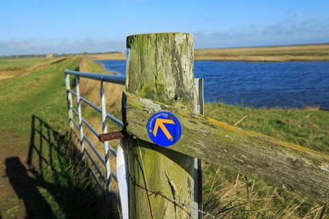Suffolk Coast path sign along flood defence wall, near Shingle Street, Suffolk, England, UK