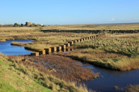 Pools of water between shingle beach and flood defence wall, Shingle Street, Suffolk, England, UK
