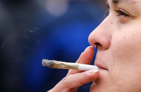 A woman smokes a joint during a demonstration in favour of legal marijuana use. The demonstrators