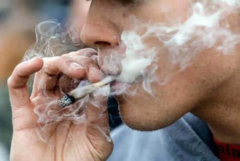 A man smokes a joint during a demonstration in favour of legal marijuana use. The demonstrators