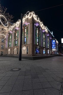 Uniquely illuminated urban building at night with eye-catching colourful windows, Quatsch Comedy