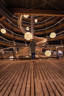 A person looks out onto a spiral-shaped, illuminated viewing platform, Enchanting forest dwellers,