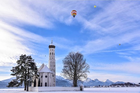 Hot air balloon over the pilgrimage church of St Coloman near Schwangau in winter, Allgäu, Swabia,