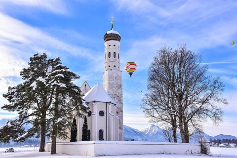 Hot air balloon over the church of St Coloman near Schwangau in winter, Allgäu, Swabia, Bavaria,