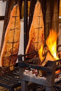 Flame-grilled salmon in a fire bowl, fillets of salmon grilled over an open flame, fish cooked,