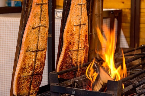 Flame-grilled salmon in a fire bowl, fillets of salmon grilled over an open flame, fish cooked,