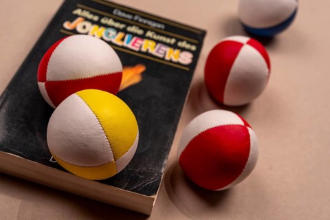 Juggling balls and a book about juggling on a white background, selective focus, studio shot,