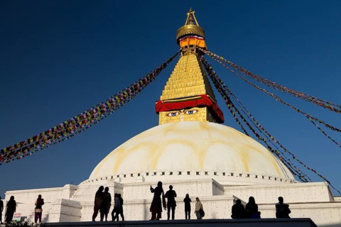 People gathered at Bouddhanath, the Bouddha Stupa, on a sunny, spring afternoon. It is the largest
