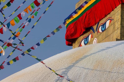 Buddhist prayer flags and eyes of Buddha, the Wisdom Eyes, painted on the golden spire of