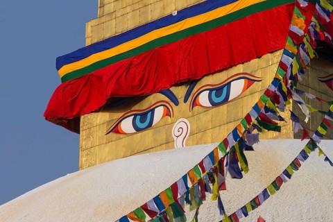 Buddhist prayer flags and eyes of Buddha, the Wisdom Eyes, painted on the golden spire of