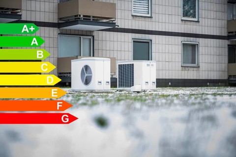 Two heat pumps in the snow in a meadow in front of an apartment block from the 1970s, graphic with