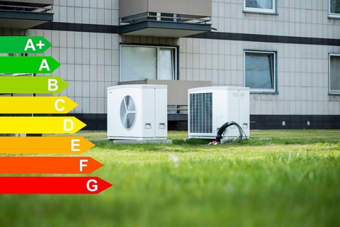Two heat pumps on a lawn of a family home, graphic with energy efficiency classes for buildings