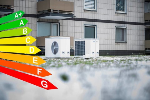 Two heat pumps in the snow in a meadow in front of an apartment block from the 1970s, graphic with