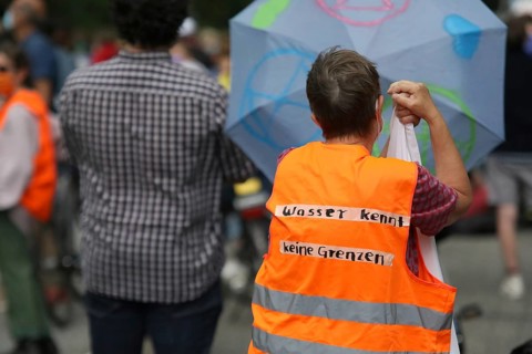 Demonstrator in a high-visibility waistcoat with the inscription Wasser kennt keine Grenzen at the