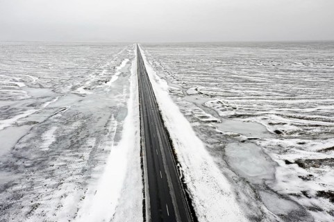 Aerial view over empty Route 1, Ring Road, two-lane national road in desolate snow covered winter