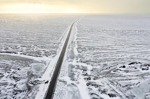 Aerial view over Route 1, Ring Road, two-lane national road in desolate snow covered winter