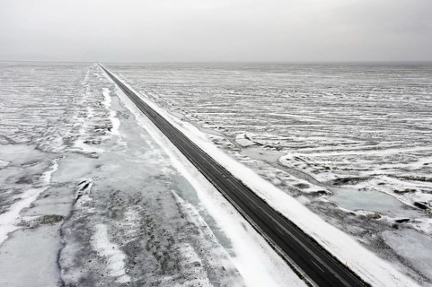 Aerial view over empty Route 1, Ring Road, two-lane national road in desolate snow covered winter