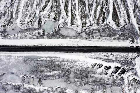 Aerial view over empty Route 1, Ring Road, two-lane national road in desolate snow covered winter