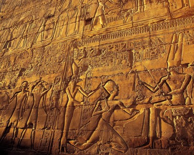 Elaborate carved stone relief with close-ups of pharonic figures in strong evening side-light, at
