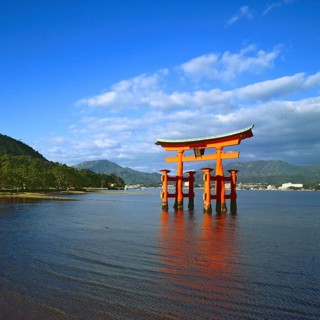 The bright red Sea-gate of Miyajima temple, Japan, against a background of sea and the low hills