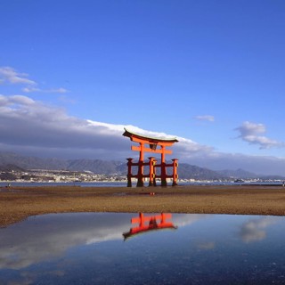 The bright red Sea-gate of Miyajima temple, Japan, against a background of sea and the low hills