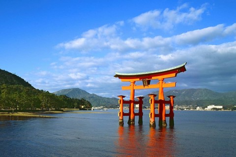 The bright red Sea-gate of Miyajima temple, Japan, against a background of sea and the low hills