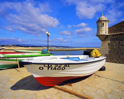 Boats on the beach at Lagos, with the old harbour defenses, the 17th century Forte Bandeira, under