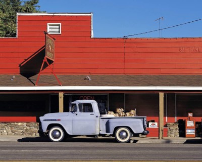 Old-style grey pick-up truck parked in front of red-painted store, California, USA, North America
